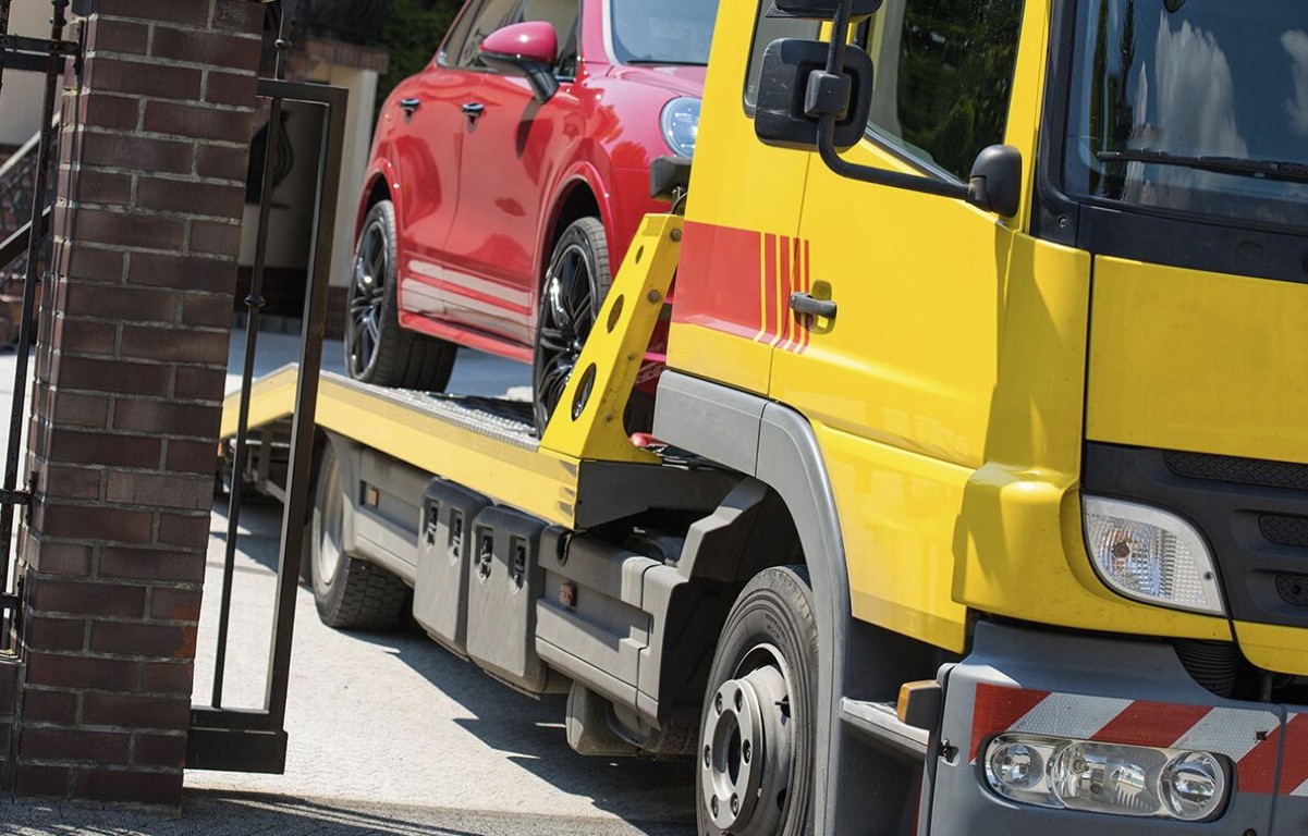 Professional towing service with yellow flatbed truck transporting vehicle in Palmview, TX